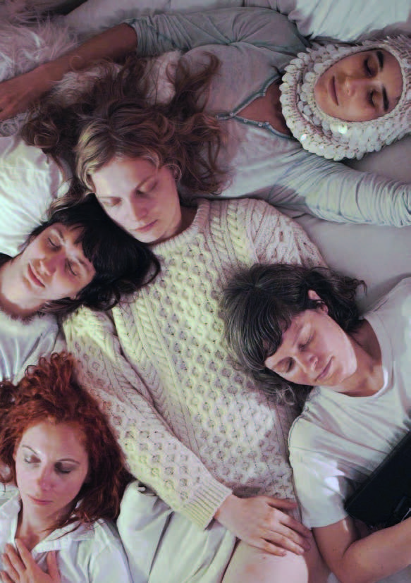 Foto von fünf Frauen. Sie sind weiß gekleidet und liegen auf einem weiß bezogenen Bett. Alle haben die Augen geschlossen.